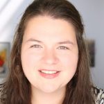 headshot of Ashley Kirk-Christman wearing a green shirt with a brick wall behind her