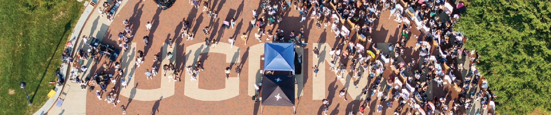 Aerial view of the word UConn on the bricks by Fairfield way filled with students at the involvement fair.
